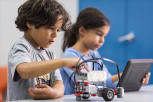 Two children work on building a robot car